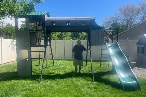 Man standing next to a playset with two girls playing