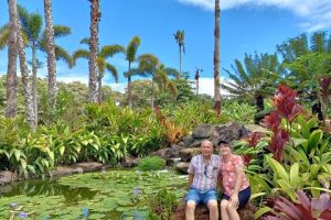 A couple sitting by a tropical pond