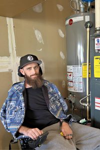 Man in a wheelchair witting by a hot water heater